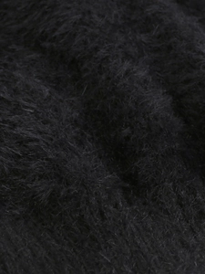 Close-up detail of soft black shaggy plush fabric texture on women's knit sweater