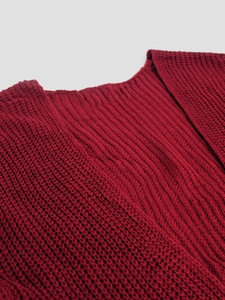 Detail of red knit cardigan showing chunky mesh hollow texture and ribbed neckline