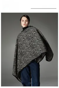 Dettaglio del poncho in maglia a motivo zebrato bianco e nero con un cappuccio alla moda