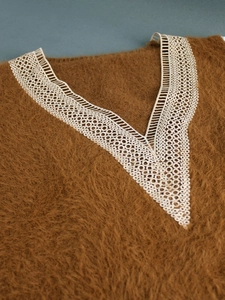 Close-up of brown longhair sweater with intricate white lace V-neck patchwork detail