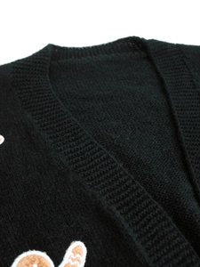 Close-up of black V-neck knitted cardigan with gingerbread man embroidery detail