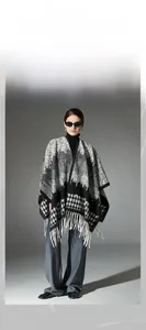 Detail of wool houndstooth shawl featuring black white geometric patterns and tassels
