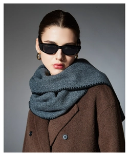 Detailed view of dark grey winter scarf with black stitching on wool coat