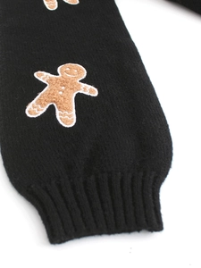 Macro detail of ribbed cuff on black knit sweater with gingerbread man embroidery
