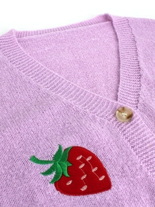 Detail of light purple knitted cardigan featuring strawberry embroidery and a button
