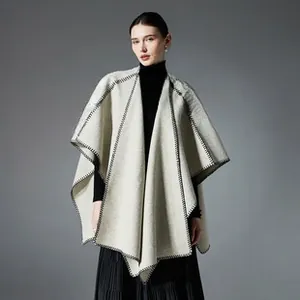 Close-up of light gray wool shawl with black contrast stitching and layered draped edges