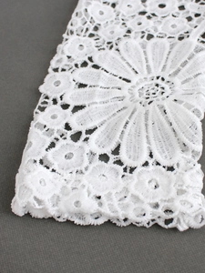 Macro shot of white lace embroidery with floral daisy patterns and delicate knit textures