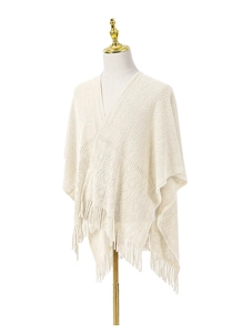Détail du châle en tricot blanc crème avec motifs ajourés et finitions à franges élégantes