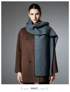 Close-up of grey oversized knit scarf with black edge stitching on brown wool coat