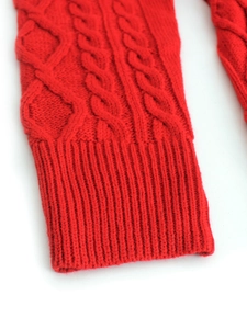 Close-up of red knit cable pattern texture and ribbed cuff detail on women's dress