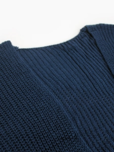 Close-up of dark blue ribbed knit fabric showing detailed texture on cardigan shoulder