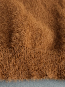 Detailed macro shot of brown lace-up mohair knit fabric showing soft fluffy texture
