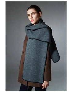 Detail of dark grey winter scarf with distinctive black whipstitch edges on wool coat