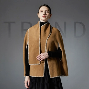 Detail of camel poncho shawl featuring bold white whipstitch edging and thick premium fabric