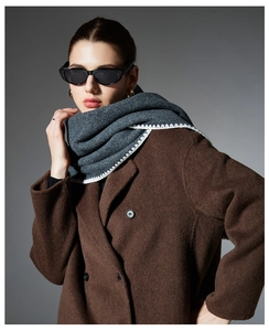 Detail of dark grey knitted scarf with distinctive white zigzag contrast stitching