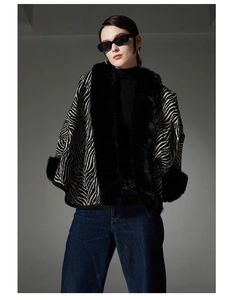 Detail of zebra pattern shawl featuring plush black faux fur trim on collar and cuffs