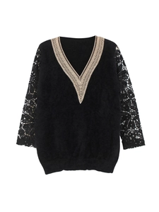 Detail of elegant black knit sweater featuring a V-neckline with delicate beige lace trim