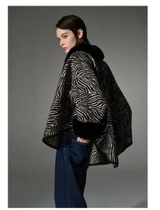 Detail shot of zebra print knit shawl featuring thick black faux fur collar and cuffs