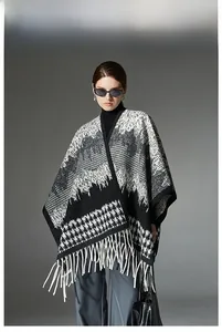 Detail of black and white houndstooth wool cape with elegant long white fringe tassels