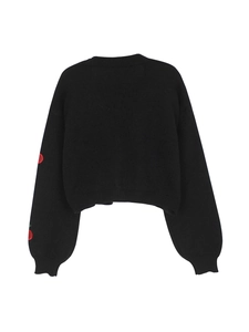 Detail view of black knit sweater back featuring red cherry embroidery on sleeves