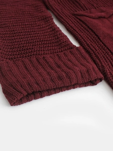 Detail view of burgundy knitted sweater sleeve with ribbed cuff and textured fabric