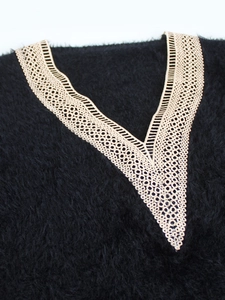 Detail view of V-neck lace trim on soft black plush knit sweater with intricate hollow lace