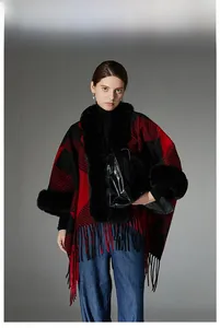 Close-up of red plaid poncho with black faux fur collar and fringe details