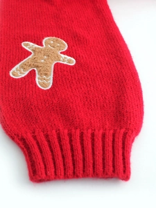 Detail showing gingerbread man patch embroidery and ribbed cuff on red knitted cardigan