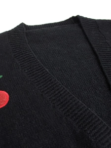 Close-up of black knitted cardigan featuring a delicate red cherry embroidery detail