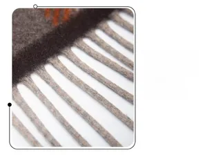 Detailed macro view of soft wool blend plaid scarf tassels in brown and orange tones