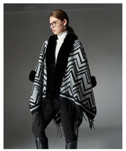 Détail du motif jacquard à vagues avec col en fausse fourrure noire et franges sur le poncho