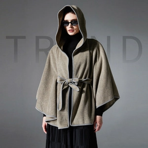 Detail of hooded wool poncho wrap featuring contrast piping and matching waist tie belt