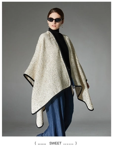 Close-up of elegant tweed poncho showing textured cream and gold woven fabric details