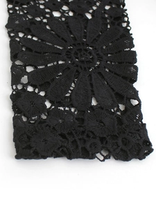 Detailed macro view of black lace sleeve with intricate floral hollow out embroidery pattern
