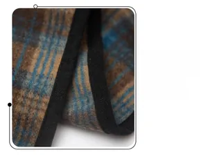 Detail of plaid patterned knit shawl showing black stitched edges and wool-like texture