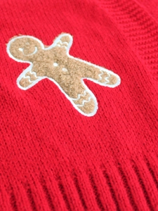 Detailed close-up of a gingerbread man patch on a red knit cardigan for women