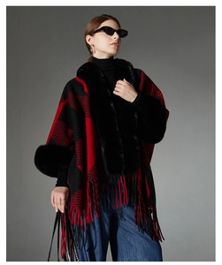 Detail of red and black plaid poncho with elegant black faux fur collar and fringe hem