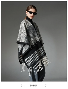 Detail of wool knit poncho with black and white houndstooth pattern and long fringe trim