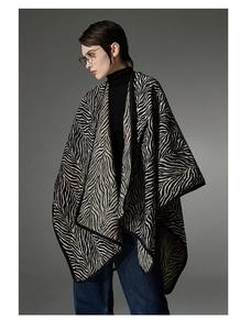 Detail shot of a knit shawl featuring black and beige zebra stripes with a hooded design