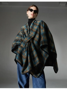 Detail of navy and tan plaid poncho cape featuring thick wool-like fabric and black piping