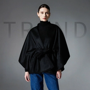 Detail of black wool cape with wide cuffs and matching waist belt for elegant styling