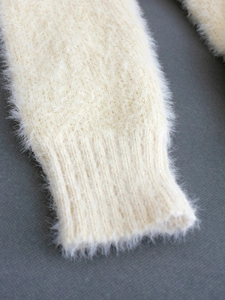 Detailed close-up of ribbed cuffs on a soft off-white long-hair knit sweater