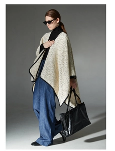 Detail of tweed cape shawl in cream gold with black trim edges and thick texture