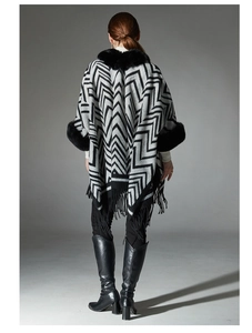 Vue détaillée du dos d'un poncho en tricot noir et gris avec garniture en fausse fourrure