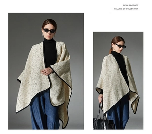 Detail of off-white tweed poncho with black trim edges and loose oversized fit