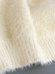 Macro shot of soft off-white knit sweater showing plush mohair texture and ribbed cuff