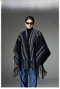 Detail of navy blue knitted poncho featuring geometric patterns and long fringe hem