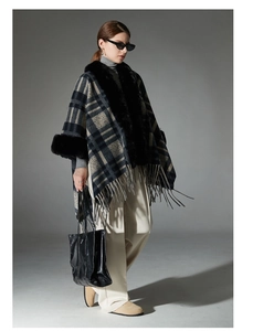 Close-up of plaid poncho cloak with faux fur collar and fringed hem in navy blue and grey