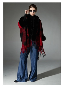 Detail showing red and black plaid shawl with faux fur collar and tassel hem on a model