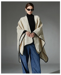 Detail of cream tweed cape shawl with black contrast trim and wool blend texture